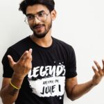 South Asian man wearing eyeglasses and a printed t-shirt posing casually in Varanasi, India.